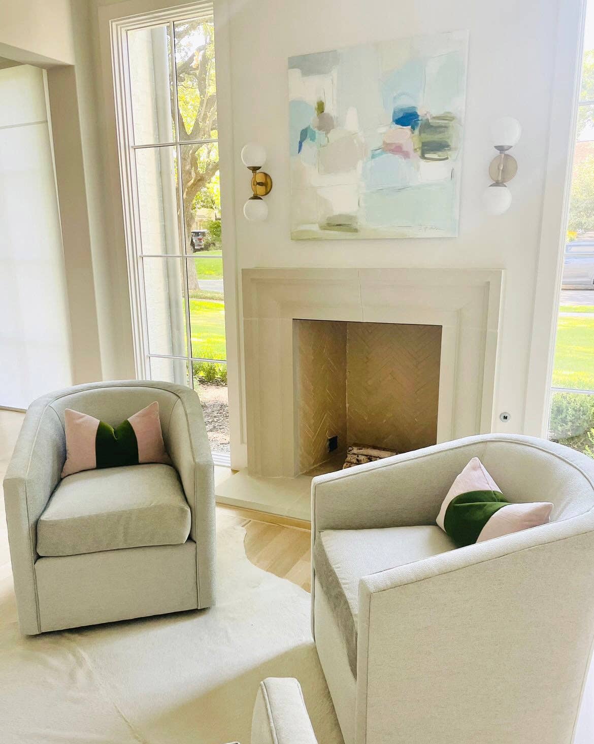 Living room with two light gray chairs, a fireplace, and abstract artwork.