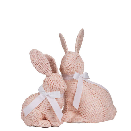 Two pink knitted bunny toys with white ribbons on a white background